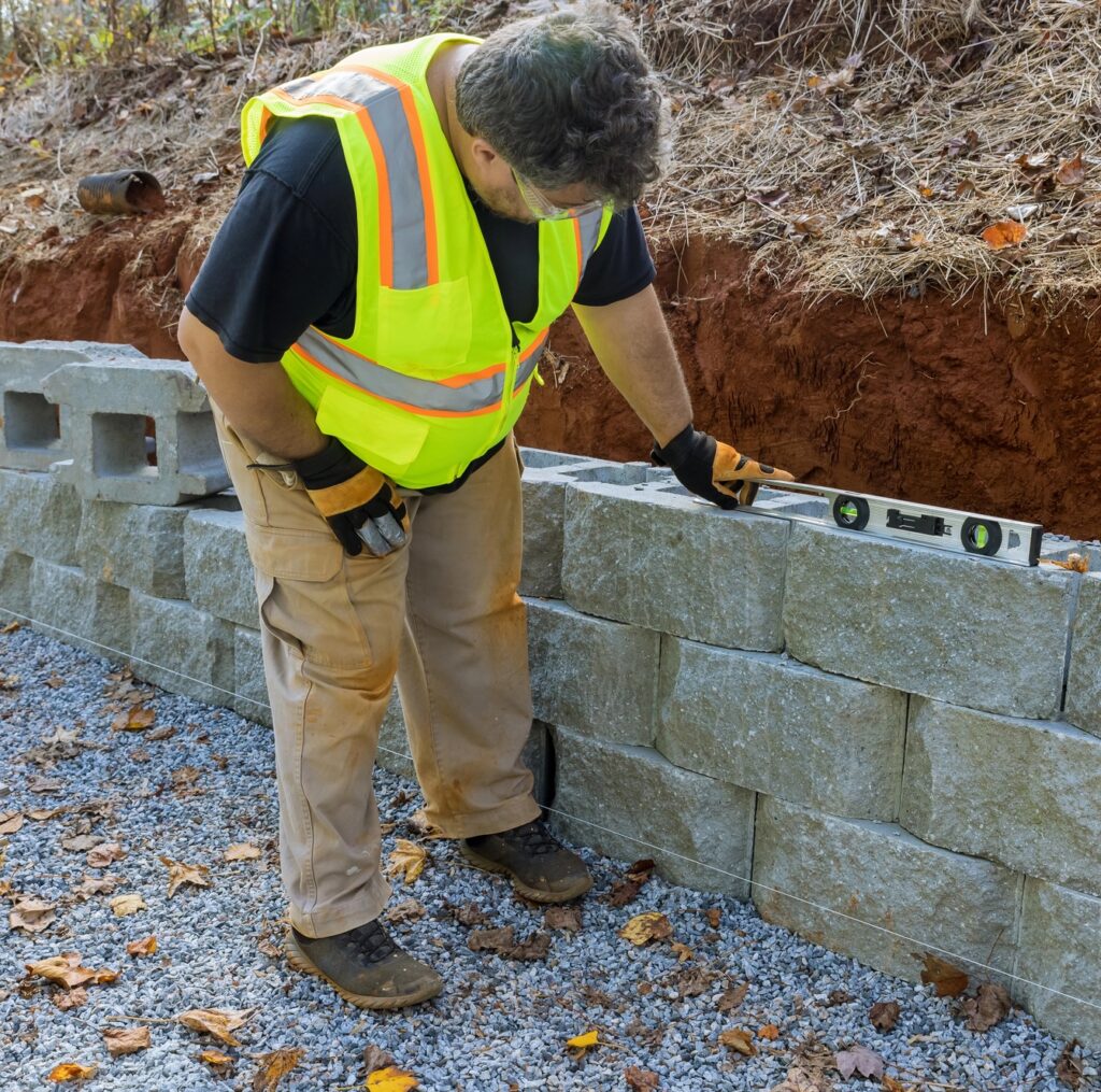Man building retaining concrete block wall